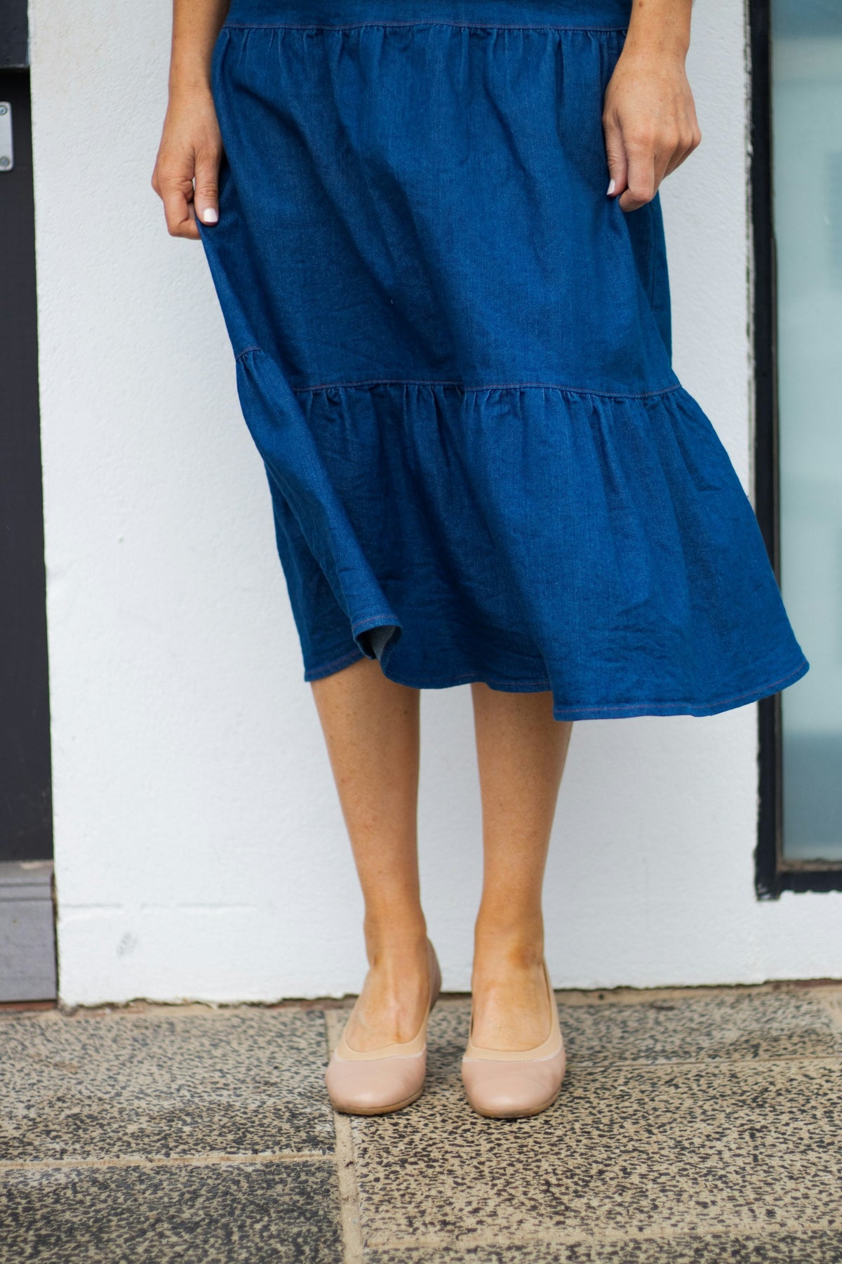Frau in blauem Kleid vor einer Tür