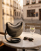 Halbmond Tasche Schwarz – auf dem Cafétisch